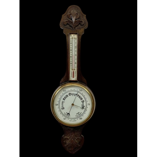 72 - An Edwardian carved oak barometer. 81cm.