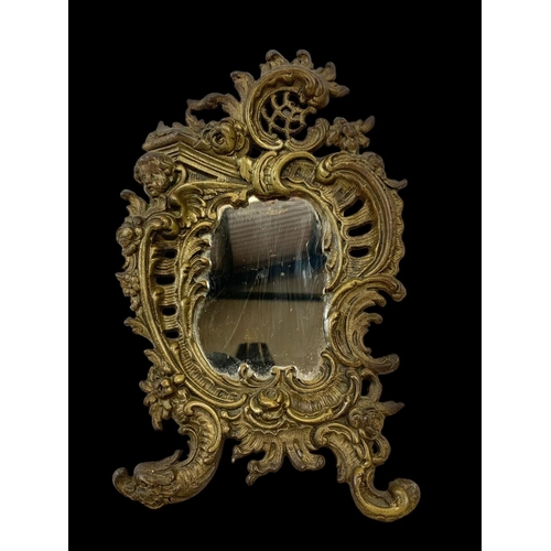 76 - A small Victorian ornate brass mirror. 19 x 31cm