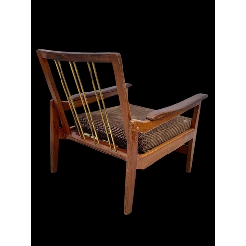 818 - A pair of teak armchairs with brass back rails and cushions. Mid century. Circa 1960’s. 72 x 65 x 70... 