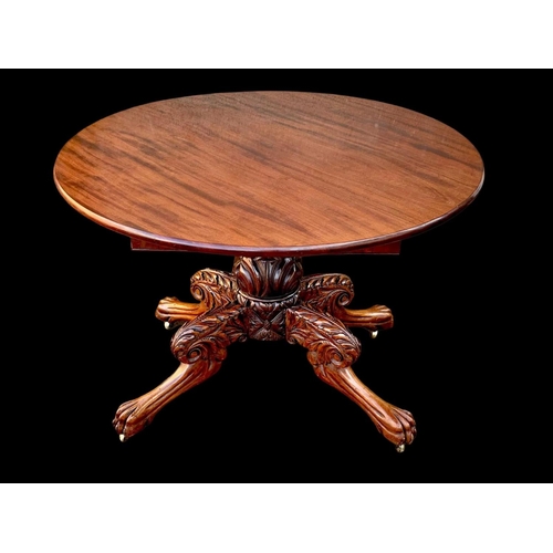 961 - An early 19th century William IV mahogany centre table with ornately carved base on lion paw feet an... 