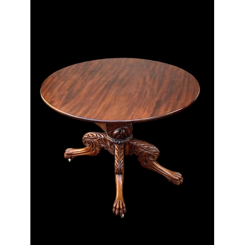 961 - An early 19th century William IV mahogany centre table with ornately carved base on lion paw feet an... 