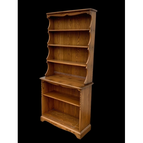 1023 - An Ercol elm shelving unit. 93 x 37 x 192cm.