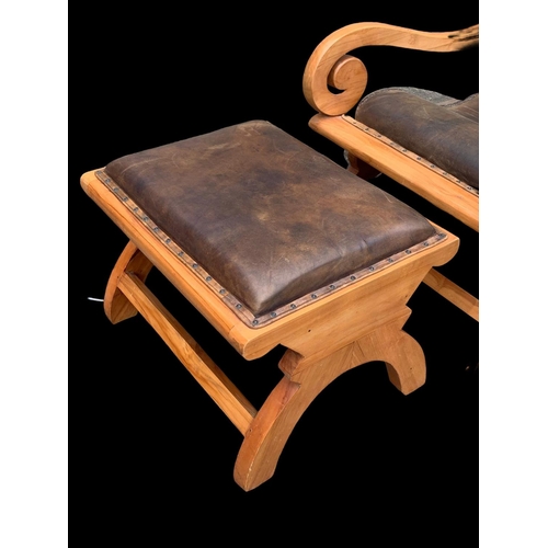 902 - A large colonial style maple and leather armchair with matching stool. 66.5 x 91 x 105cm.