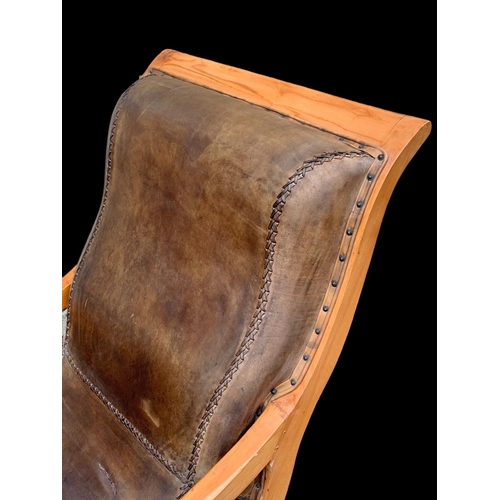 902 - A large colonial style maple and leather armchair with matching stool. 66.5 x 91 x 105cm.