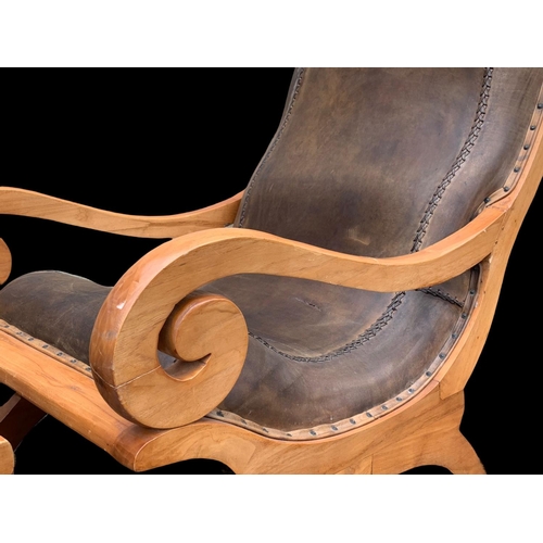 902 - A large colonial style maple and leather armchair with matching stool. 66.5 x 91 x 105cm.