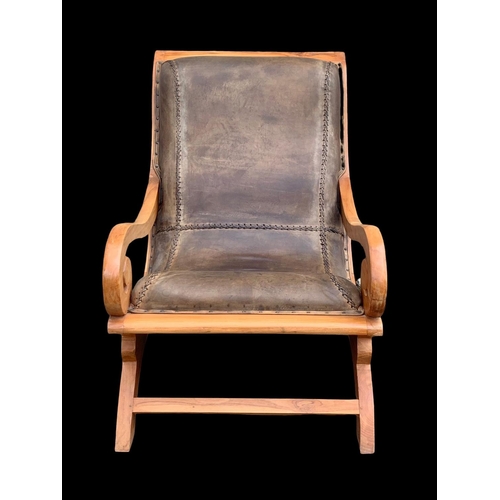 903 - A large colonial style maple and leather armchair with matching stool. 66.5 x 91 x 105cm