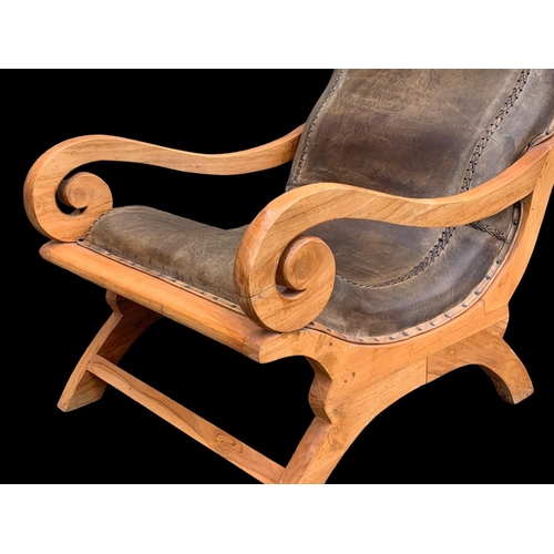 903 - A large colonial style maple and leather armchair with matching stool. 66.5 x 91 x 105cm