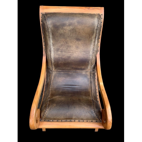 903 - A large colonial style maple and leather armchair with matching stool. 66.5 x 91 x 105cm