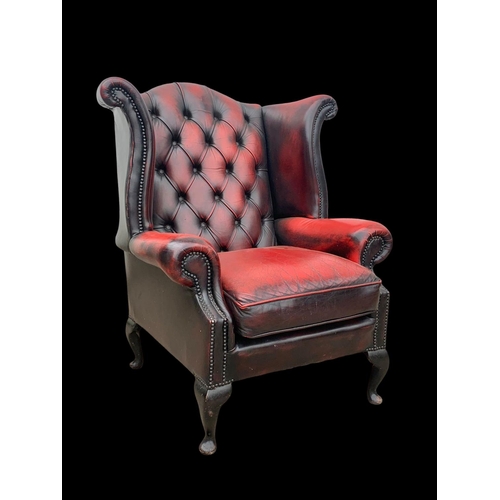 959 - A deep button Ox-Blood leather wingback armchair.