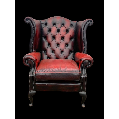 959 - A deep button Ox-Blood leather wingback armchair.