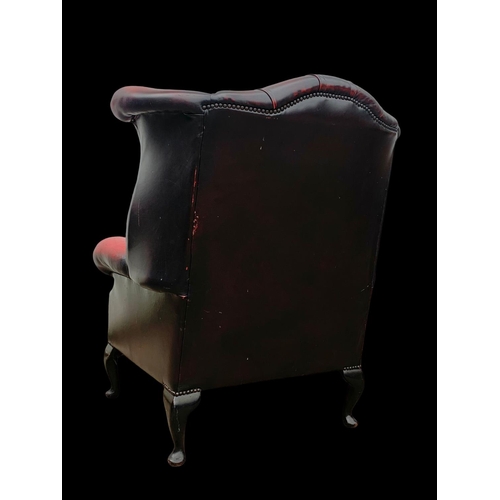 959 - A deep button Ox-Blood leather wingback armchair.