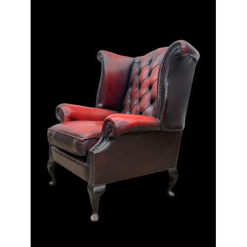 959 - A deep button Ox-Blood leather wingback armchair.