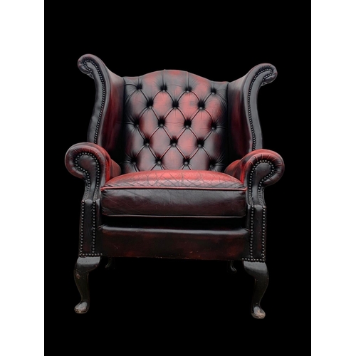 959 - A deep button Ox-Blood leather wingback armchair.