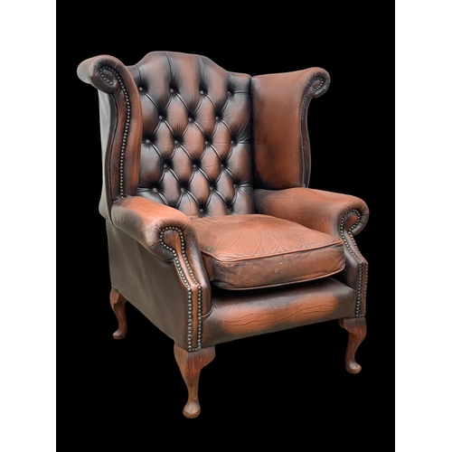 960 - A large deep button leather wingback armchair.