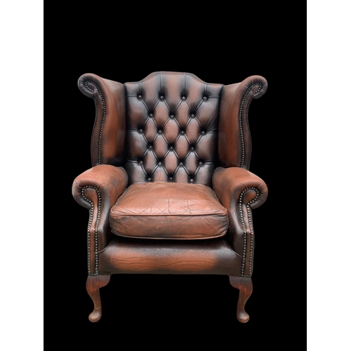 960 - A large deep button leather wingback armchair.