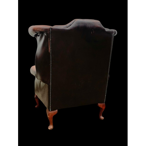 960 - A large deep button leather wingback armchair.