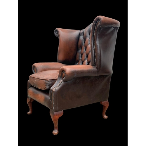 960 - A large deep button leather wingback armchair.