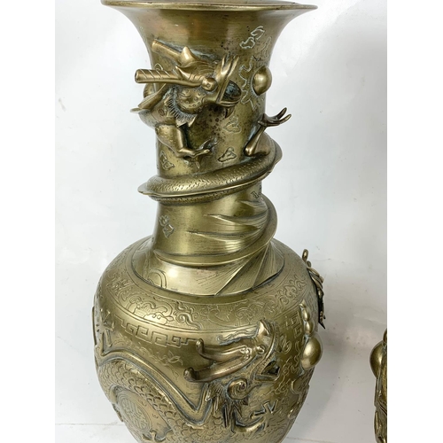 254 - A pair of large early 20th century brass Oriental vases with dragon decoration.  42cm