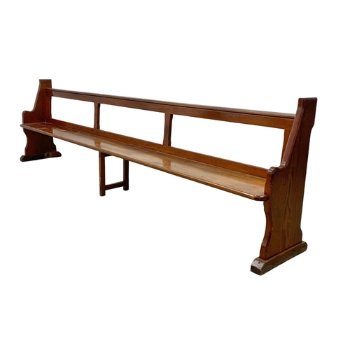 1102 - A large early 20th century pitch pine church pew/bench. 334cm.