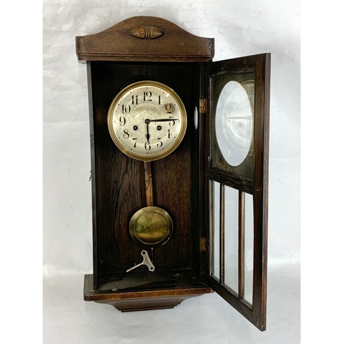 158 - An early 20th century oak cased wall clock. With key and pendulum. 75cm