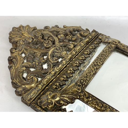 185 - An ornate brass framed bevelled mirror. 31 x 57.5cm