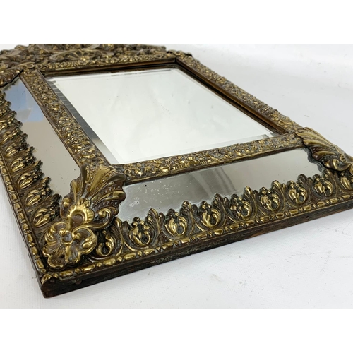 185 - An ornate brass framed bevelled mirror. 31 x 57.5cm