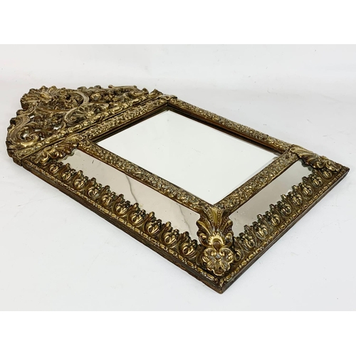 185 - An ornate brass framed bevelled mirror. 31 x 57.5cm