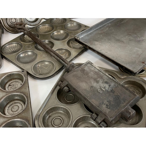 364 - A quantity of Edwardian baking trays and a cast iron waffle maker.