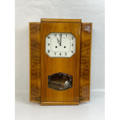 369 - A vintage walnut wall clock. With key and pendulum. 46 x 62cm