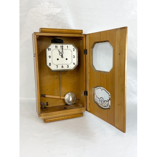 369 - A vintage walnut wall clock. With key and pendulum. 46 x 62cm