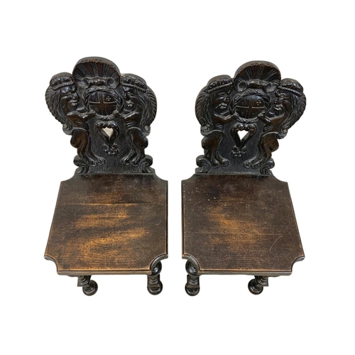 827 - A pair of 19th century continental carved oak hall chairs in the medieval style. Circa 1880.