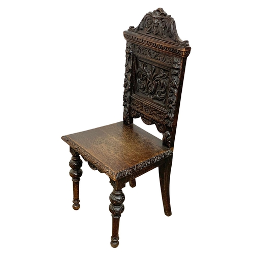 859 - A late Victorian carved oak hall chair. Circa 1880. Ground to back 108cm