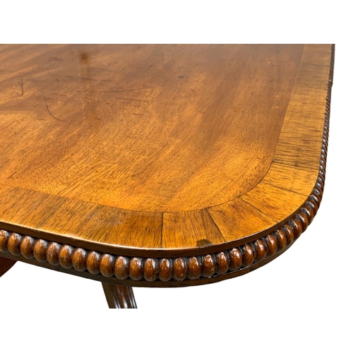 860 - A large George IV mahogany tilt top pedestal dining table, with rosewood cross banding, gadrooned ed... 