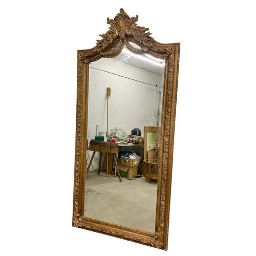 894 - A very large heavily gilt framed mirror. 100 x 214cm