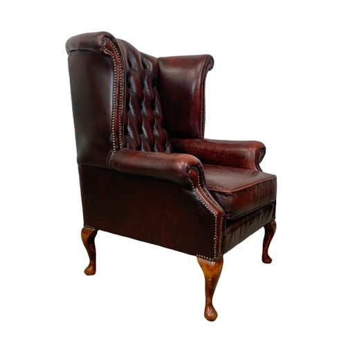 909 - A deep button ox-blood leather wingback armchair.