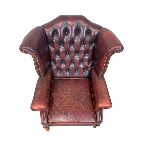 909 - A deep button ox-blood leather wingback armchair.