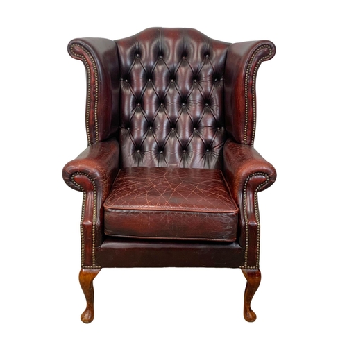 909 - A deep button ox-blood leather wingback armchair.