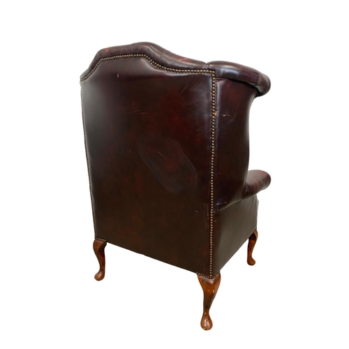 909 - A deep button ox-blood leather wingback armchair.