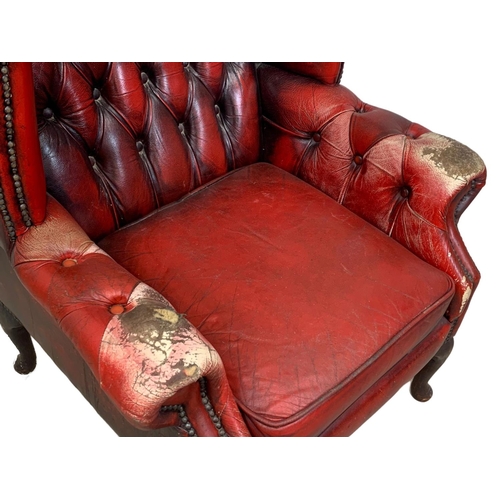 945 - A deep button ox-blood leather wingback armchair.