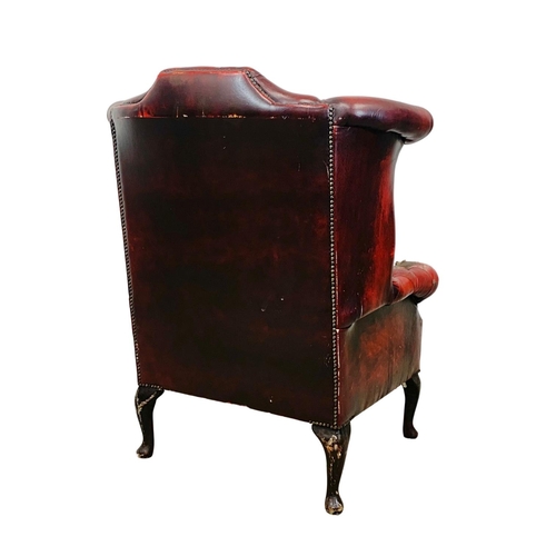 945 - A deep button ox-blood leather wingback armchair.