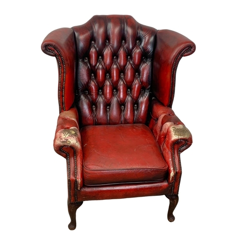 945 - A deep button ox-blood leather wingback armchair.