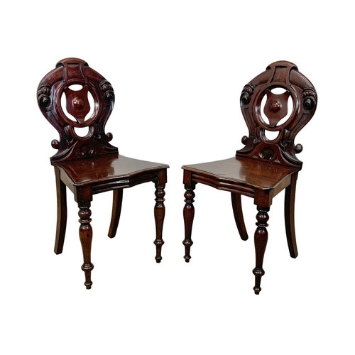 872 - A pair Victorian carved mahogany hall chairs.