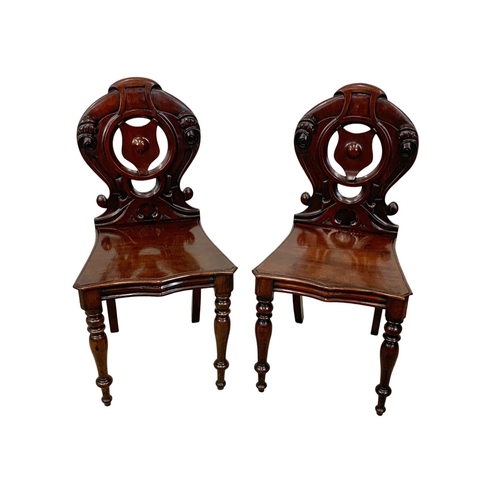 872 - A pair Victorian carved mahogany hall chairs.