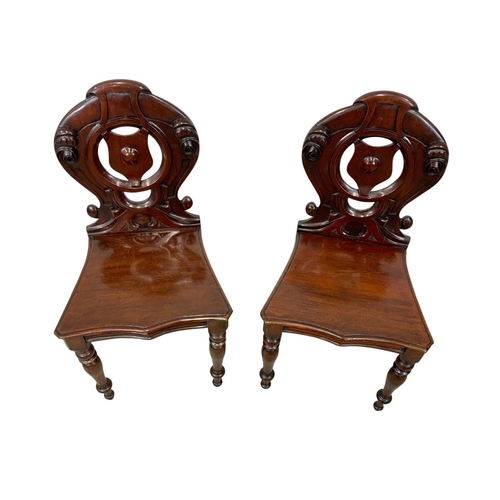 872 - A pair Victorian carved mahogany hall chairs.