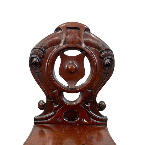 872 - A pair Victorian carved mahogany hall chairs.