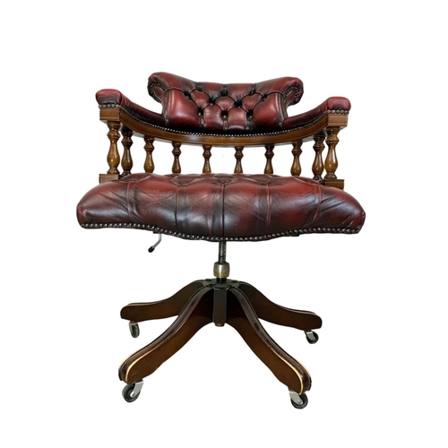 822 - A deep button leather ox-blood swivel captains desk chair.