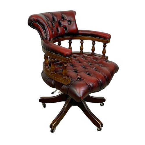 822 - A deep button leather ox-blood swivel captains desk chair.