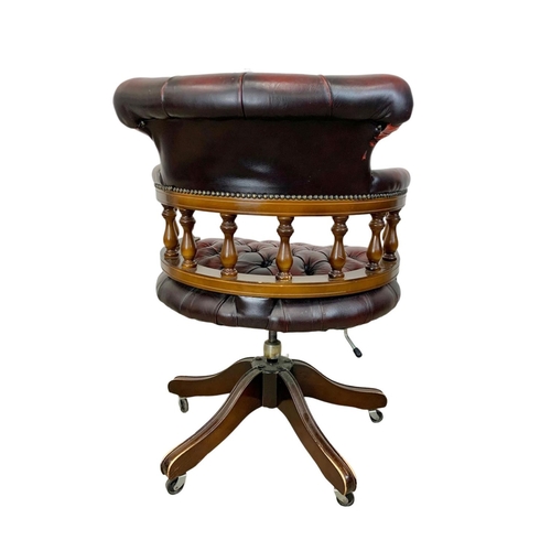 822 - A deep button leather ox-blood swivel captains desk chair.