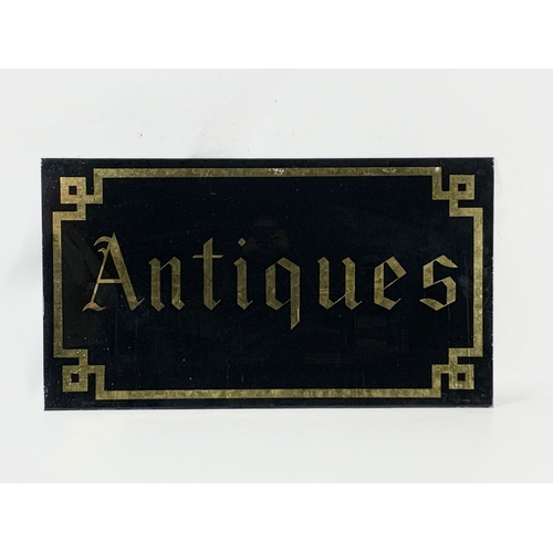 70 - A vintage glass “Antiques” sign. 109.5 x 61cm.