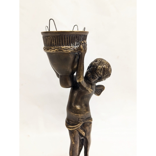 136 - A vintage bronze cherub candle holder. 24cm